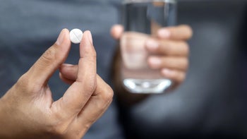 Health: Pramipexole: closeup white pill hand and water 1220131899