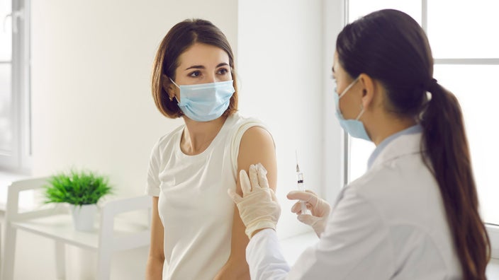 A healthcare provider talking to their patient before injecting a vaccine.