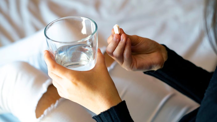 A teenage girl prepares to take medication with a glass of water.