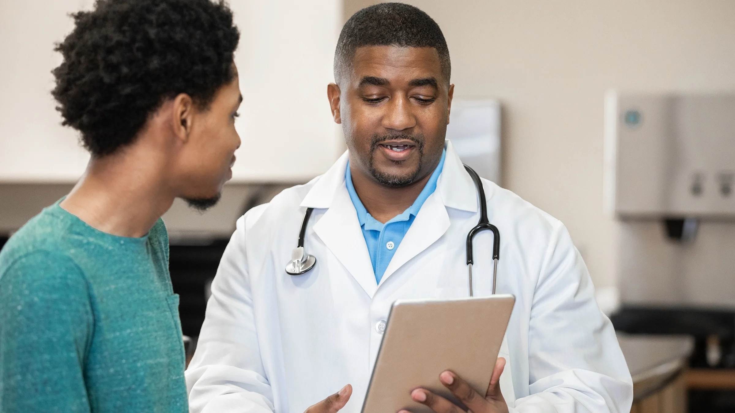 Healthcare professional holding digital tablet and discussing test results with patient.