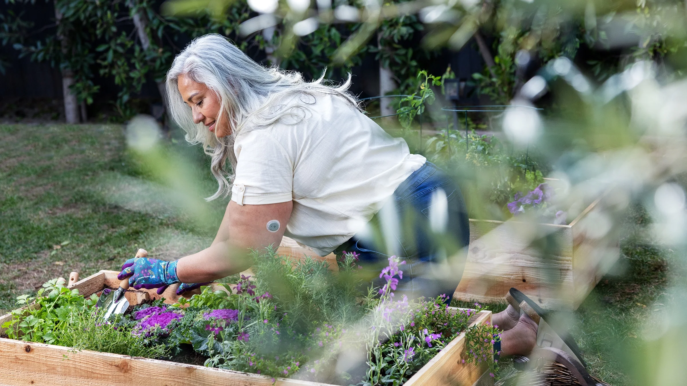 A woman works in her garden while wearing a Dexcom Stelo, a continuous glucose monitor.