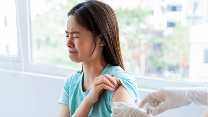 Nervous woman sitting while receiving injection.