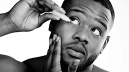 Black and white close-up of a man putting eye drops in his right eye on a white background.
PeopleImages/iStock via Getty Images