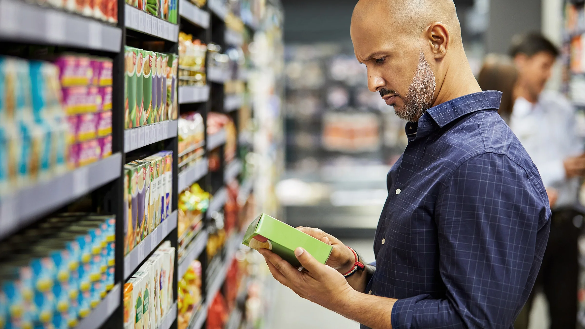 Man reading food label in a grocery store.