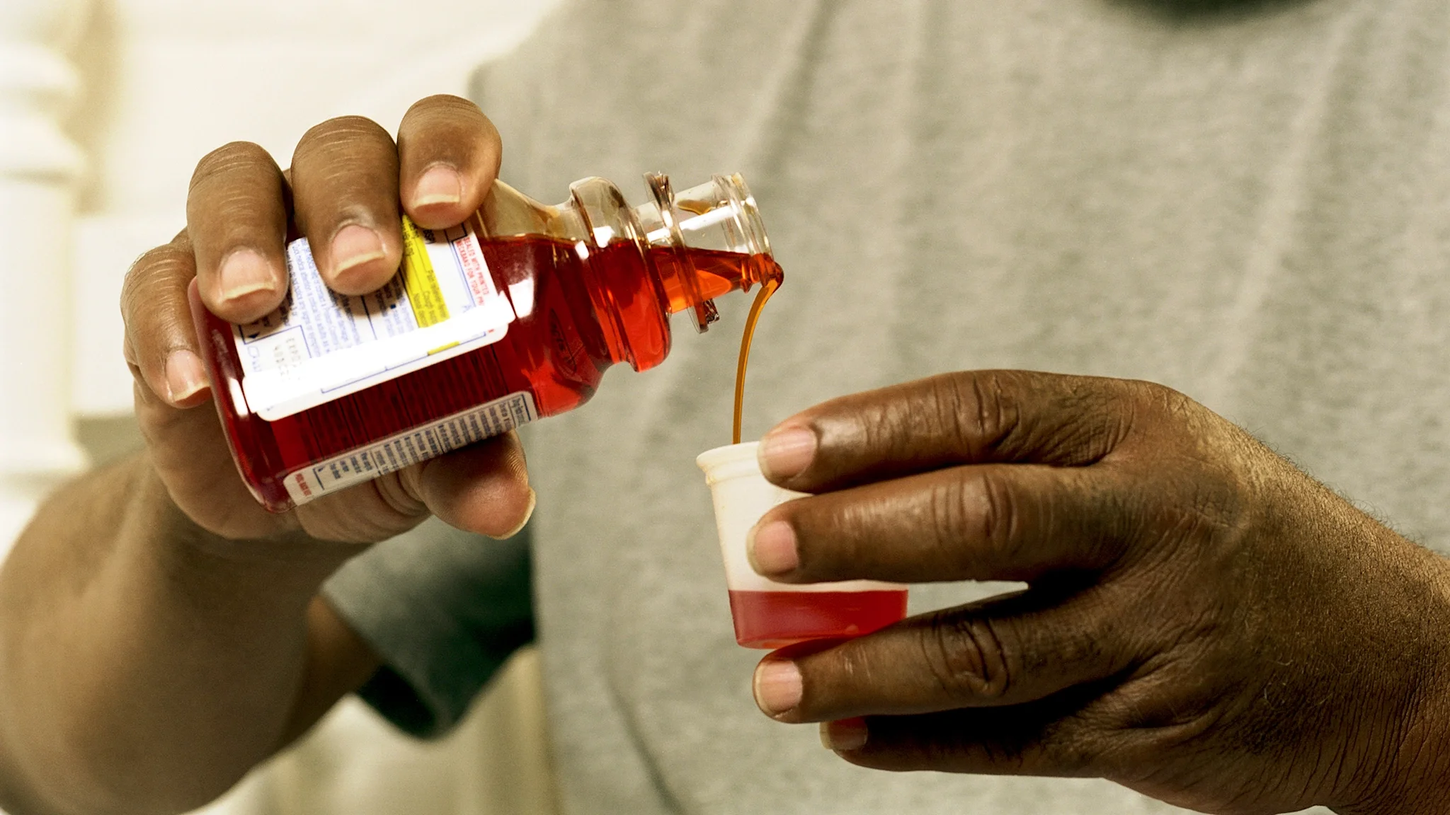 Older man pouring medicine into medicine cup