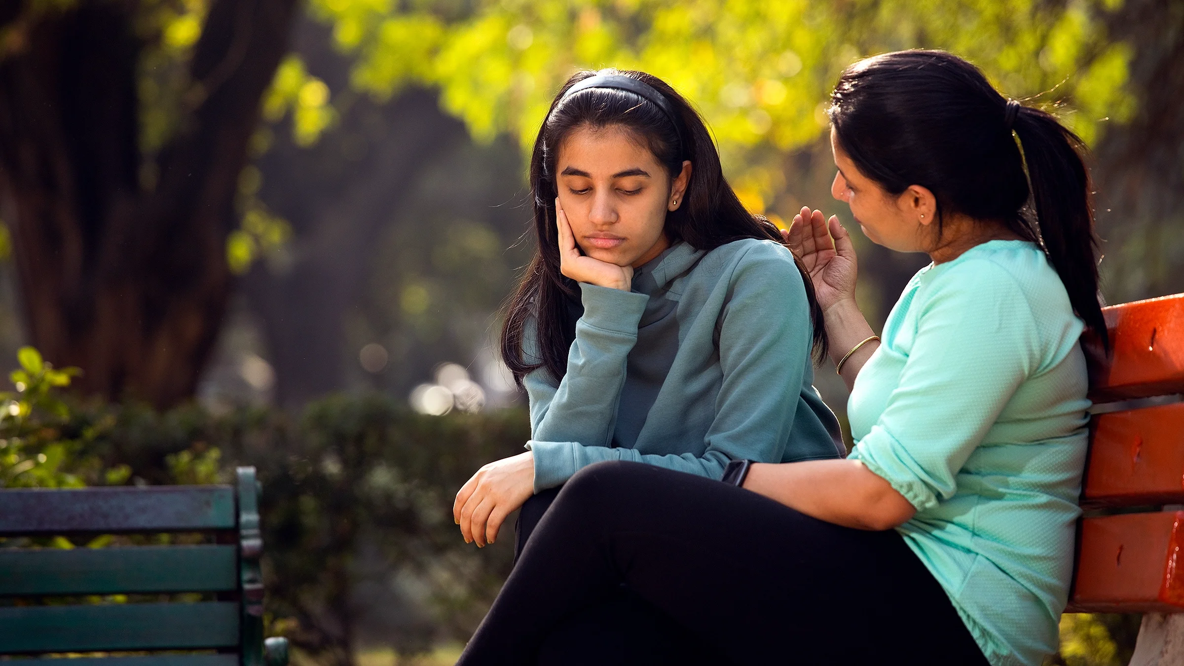 Mother comforting her stressed daughter at a park.