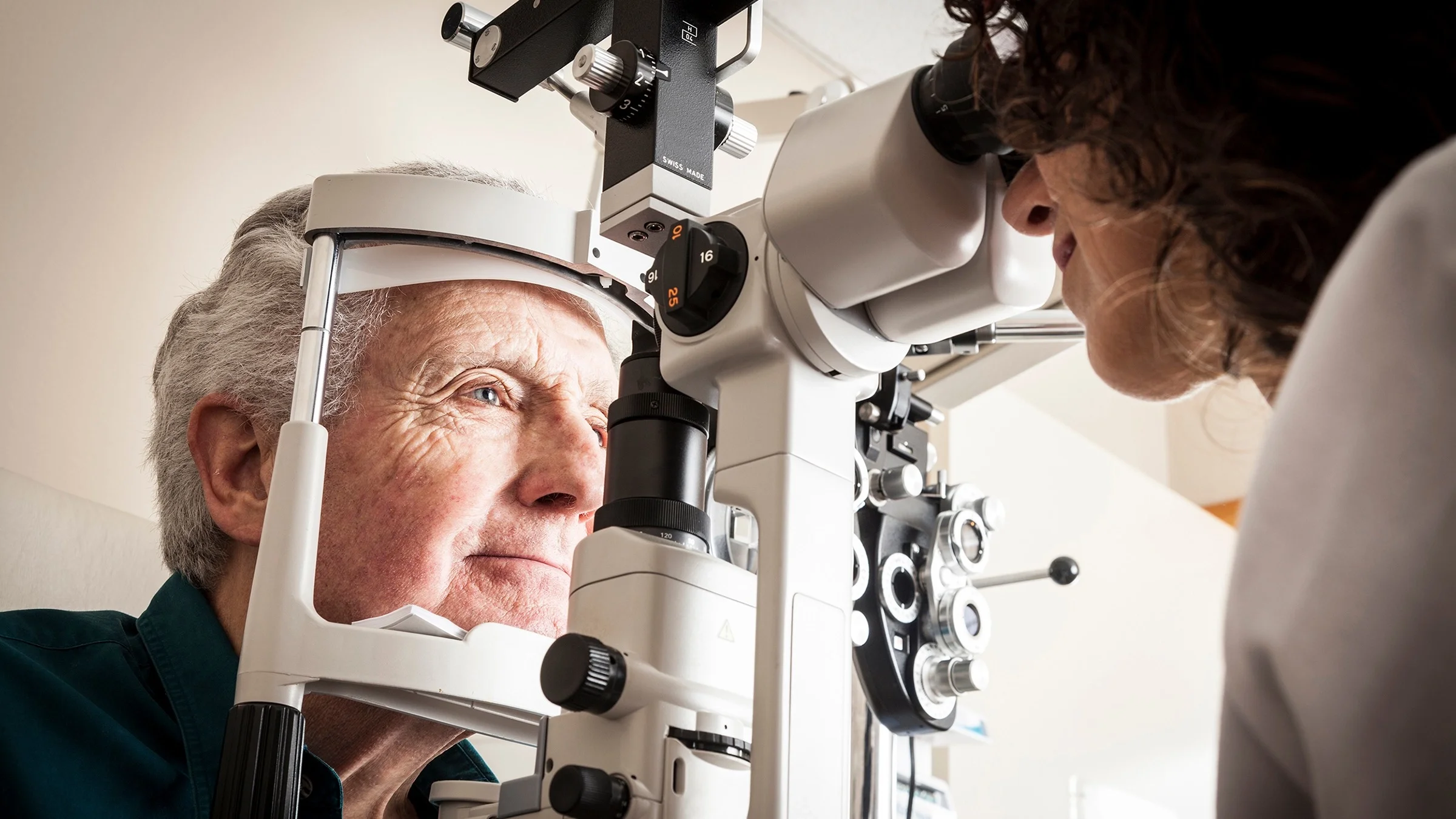 Close-up of an elderly man at his eye exam. He has his head in place resting on the eye exam equipment.
