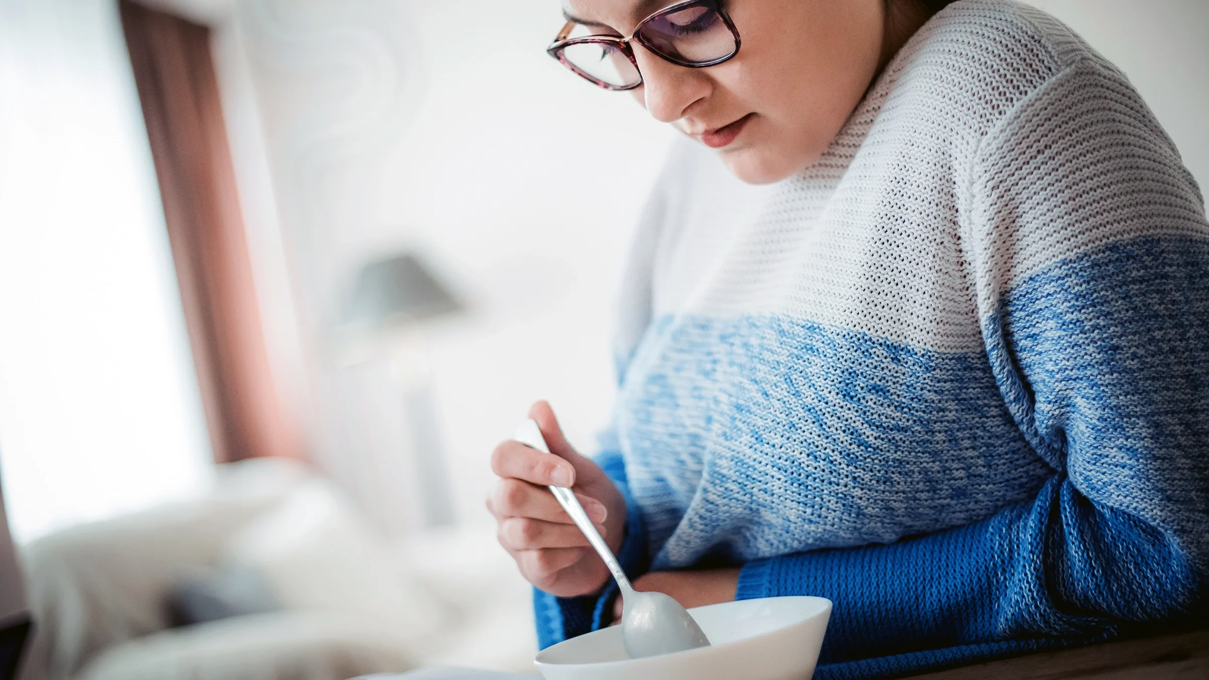 A teenage girl eats out of a bowl. Ultra-processed foods can affect mental health.