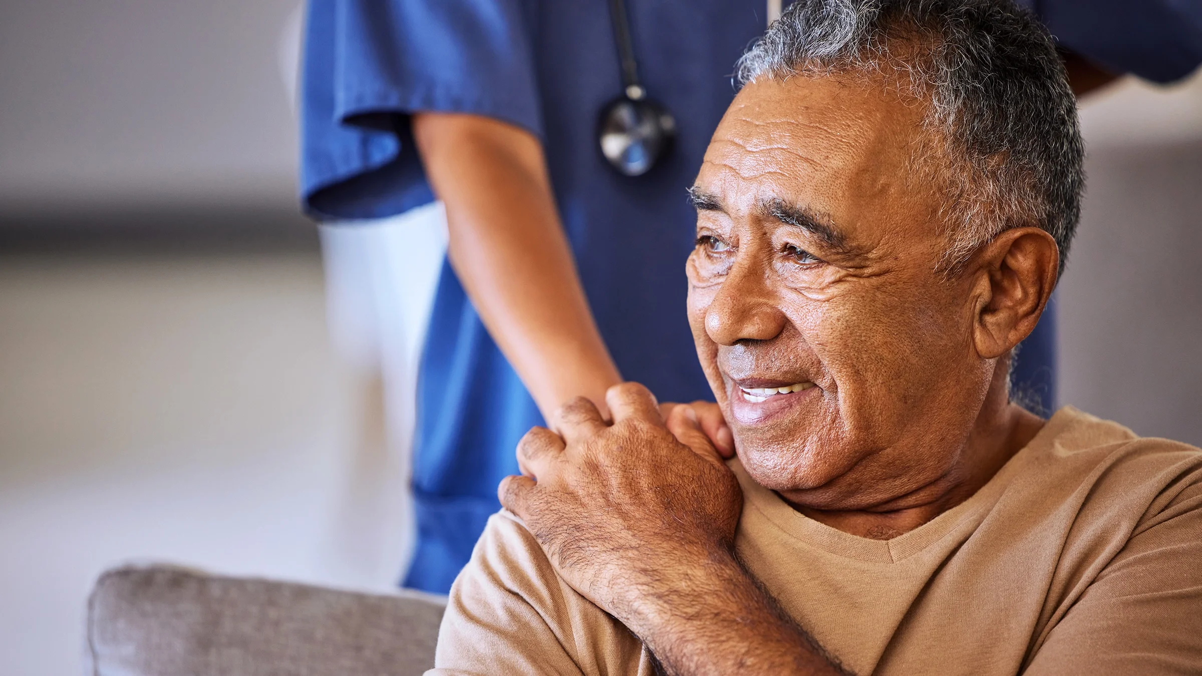 A caregiver holds the hand of a smiling patient.