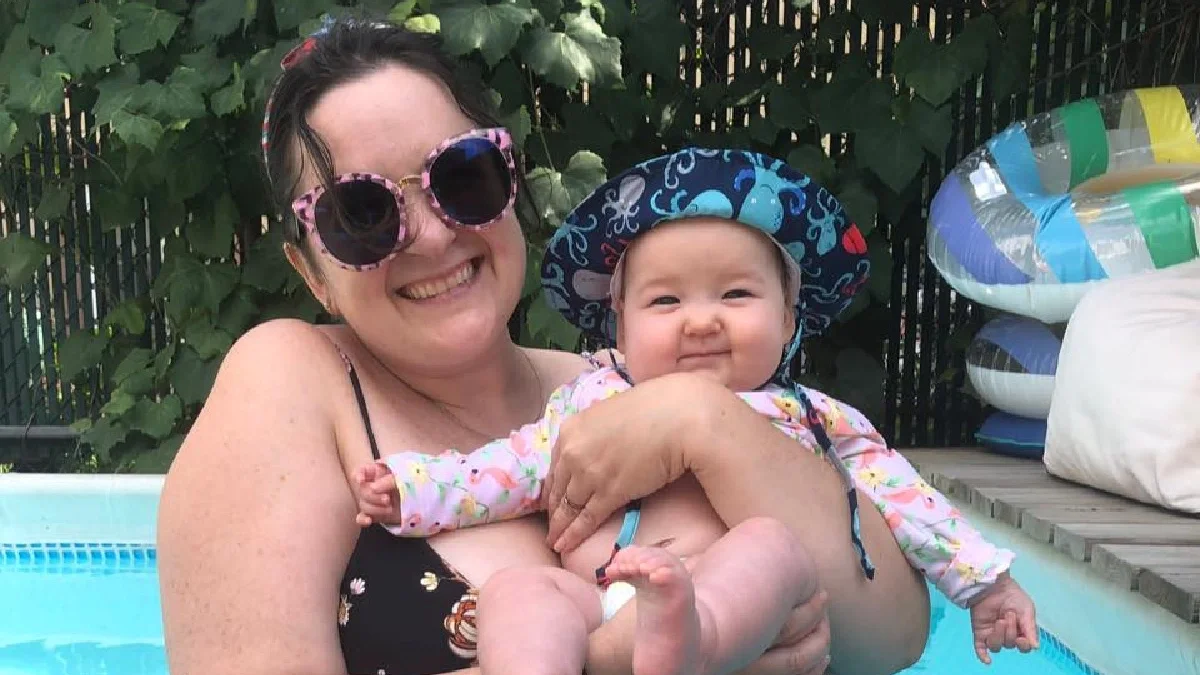 Woman standing in pool holding her baby