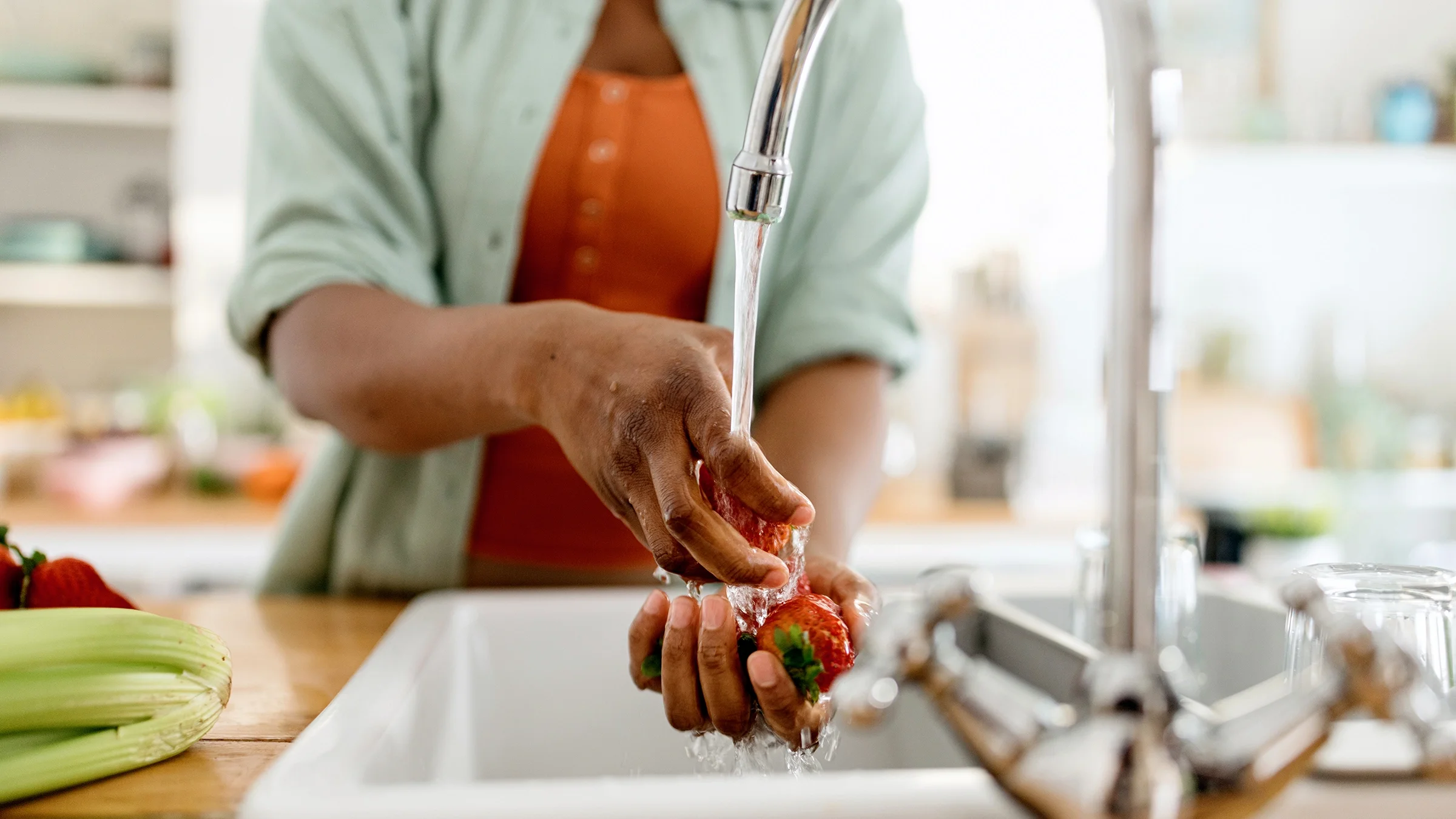 A woman washes strawberries in her kitchen sink. Some fruits are ripened with calcium carbide.