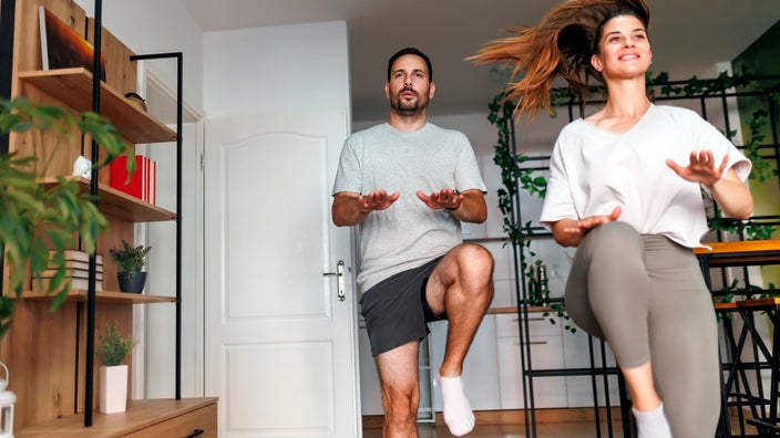 A couple does high knee exercises at home.