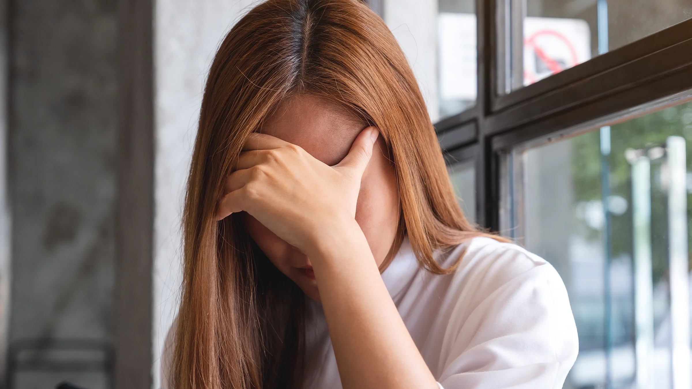 Woman with a headache covering her eyes and forehead with her hand.