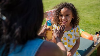 Dermatology: mom applying sunscreen on daughters face-1334431945