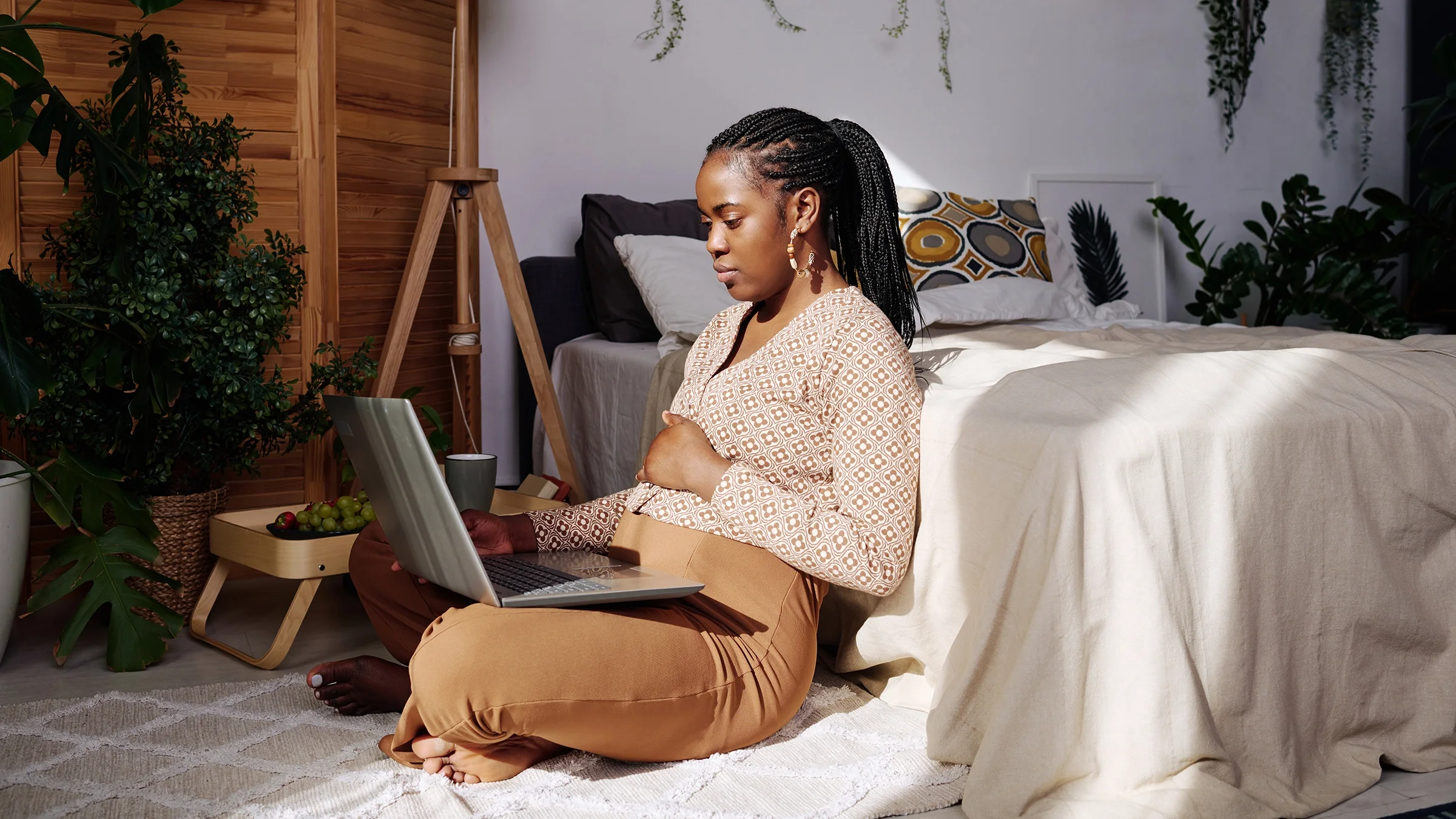 Woman sitting on the floor in her bedroom with laptop