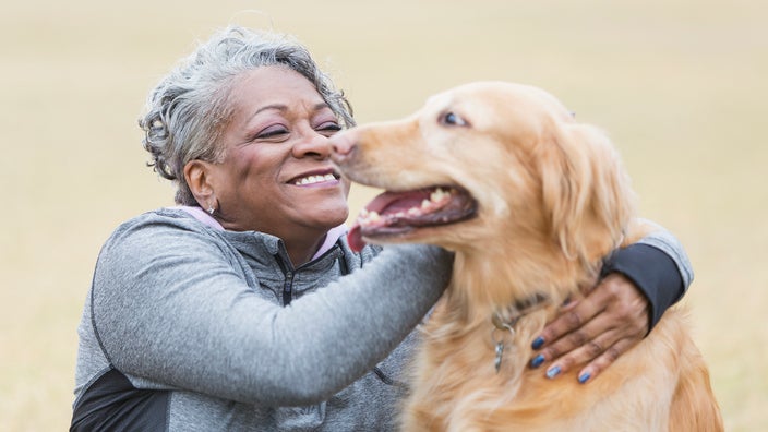 Older woman smiling and hugging her golden retriever.