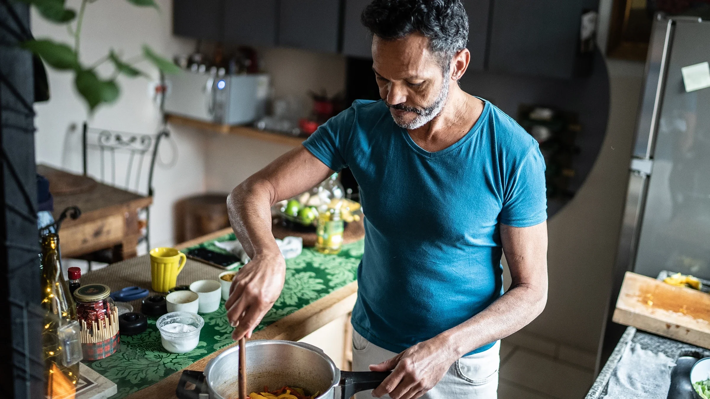 A man stirs ingredients in a pot as he cooks in his kitchen at home.