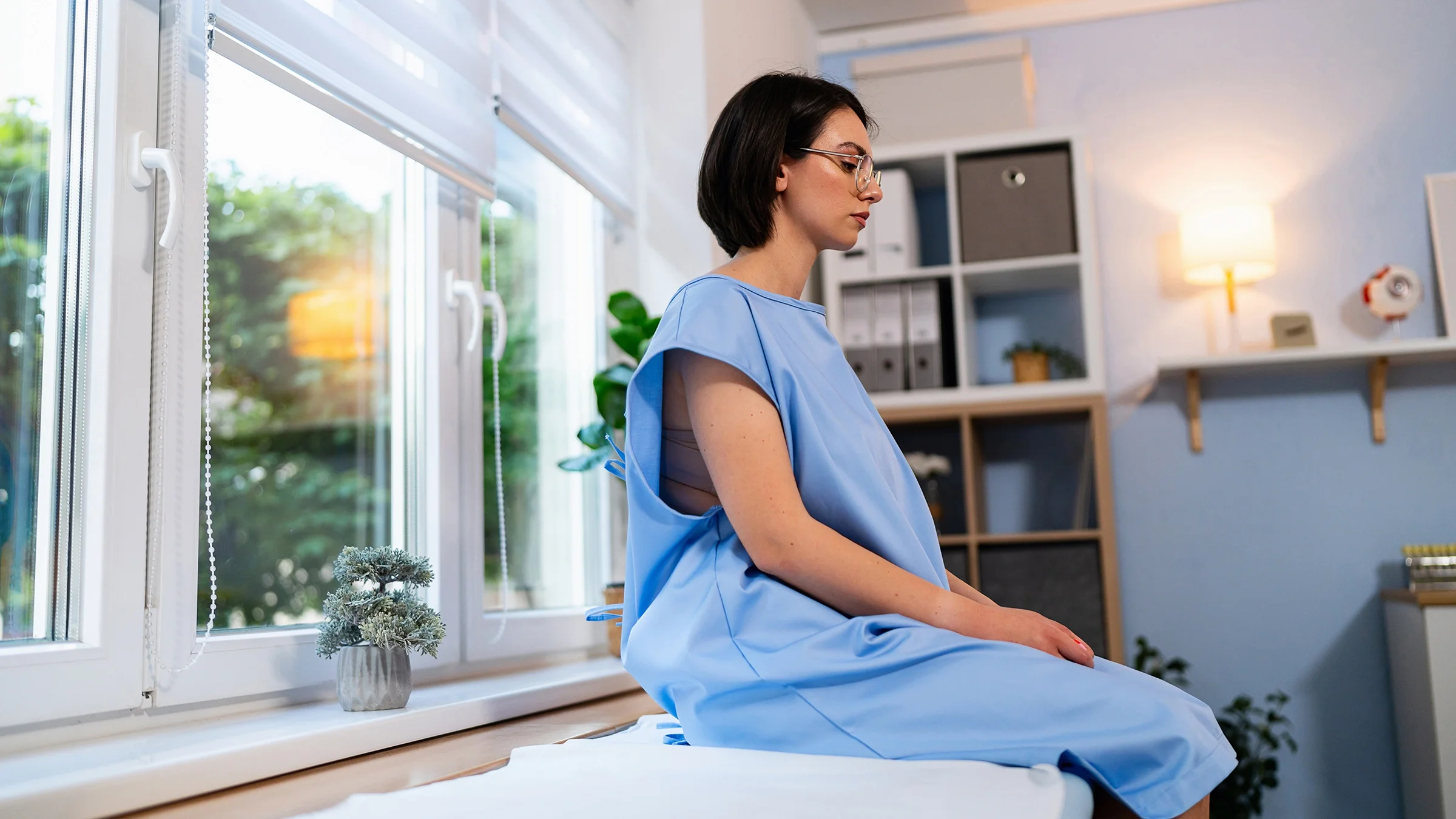 Woman sitting on examination table in a hospital gown