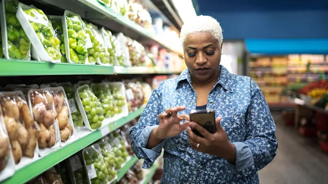 Health: Sucralfate: woman using smartphone in supermarket 1221447841