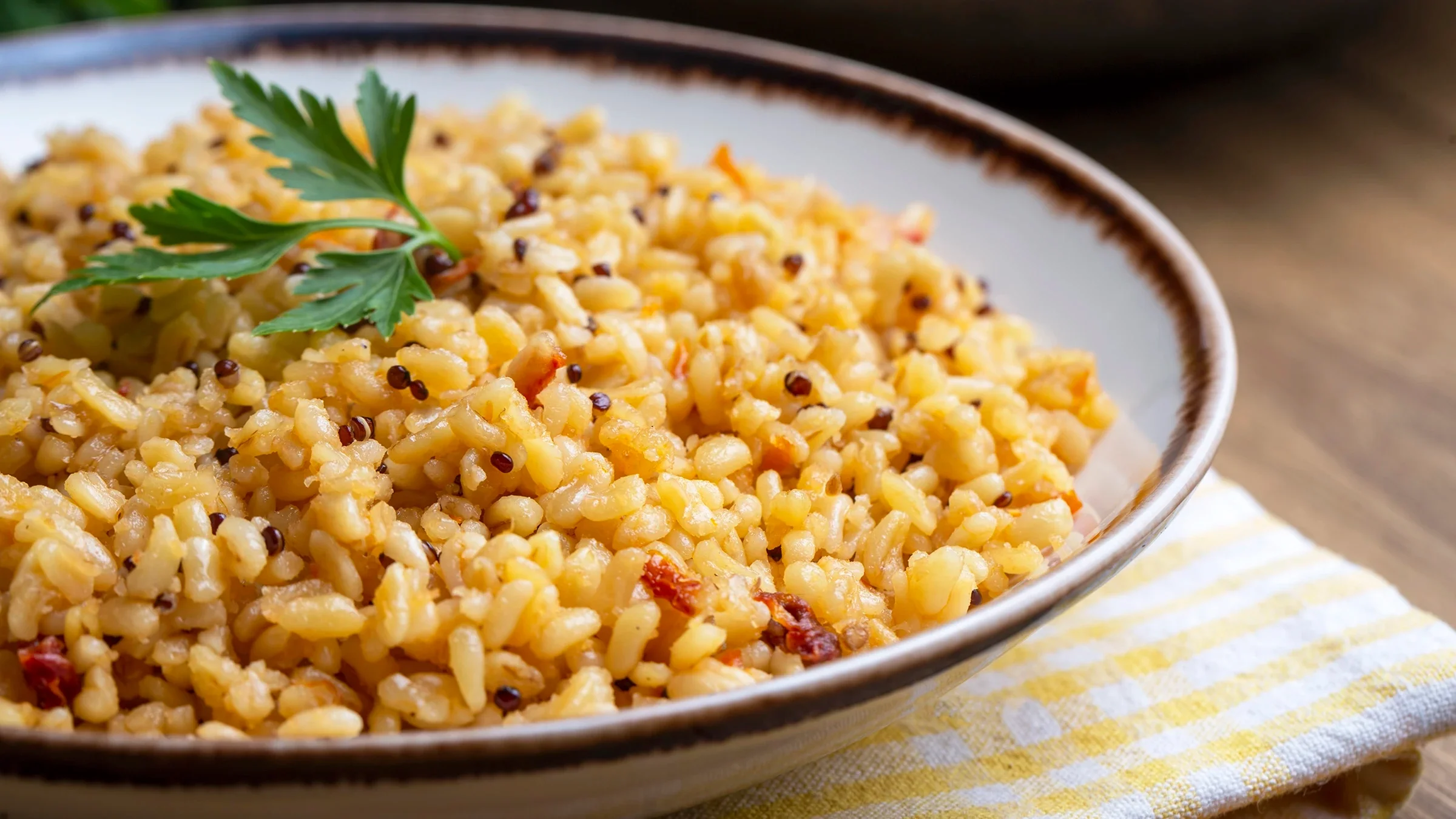 A bowl filled with bulgur and quinoa is on a table.
