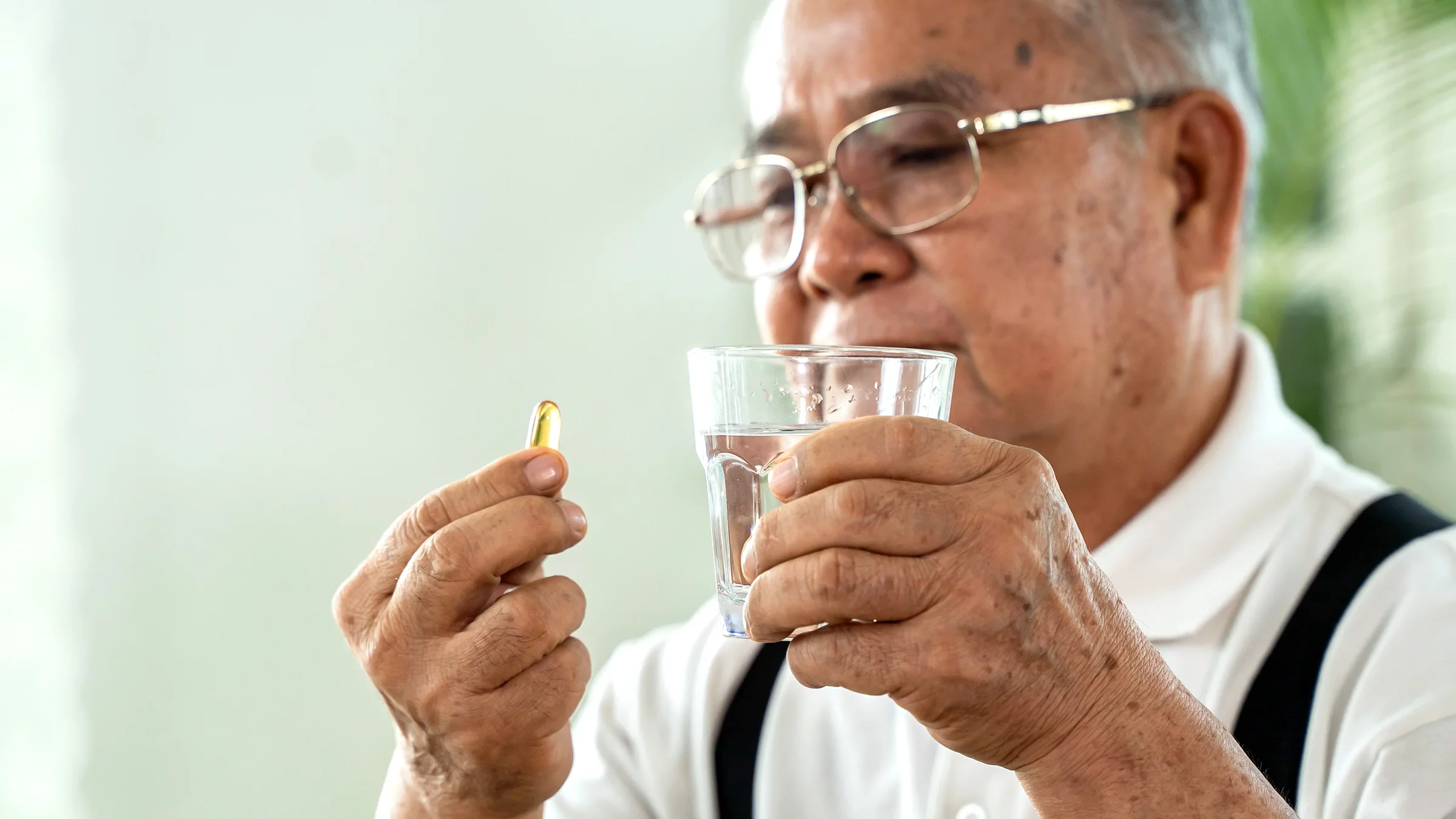 A man prepares to take a fish oil supplement with a glass of water.