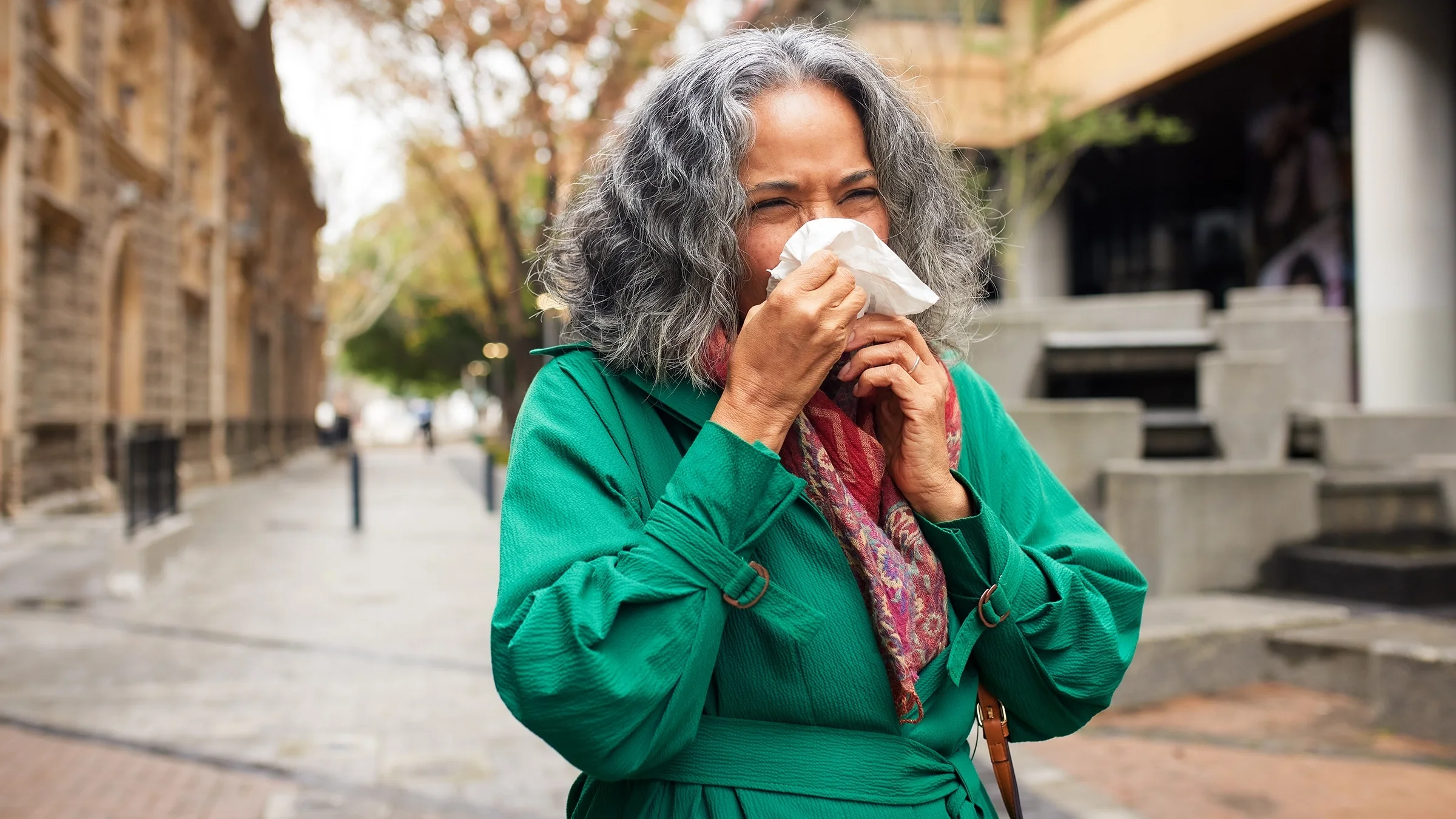 A woman is sneezing into a tissue.