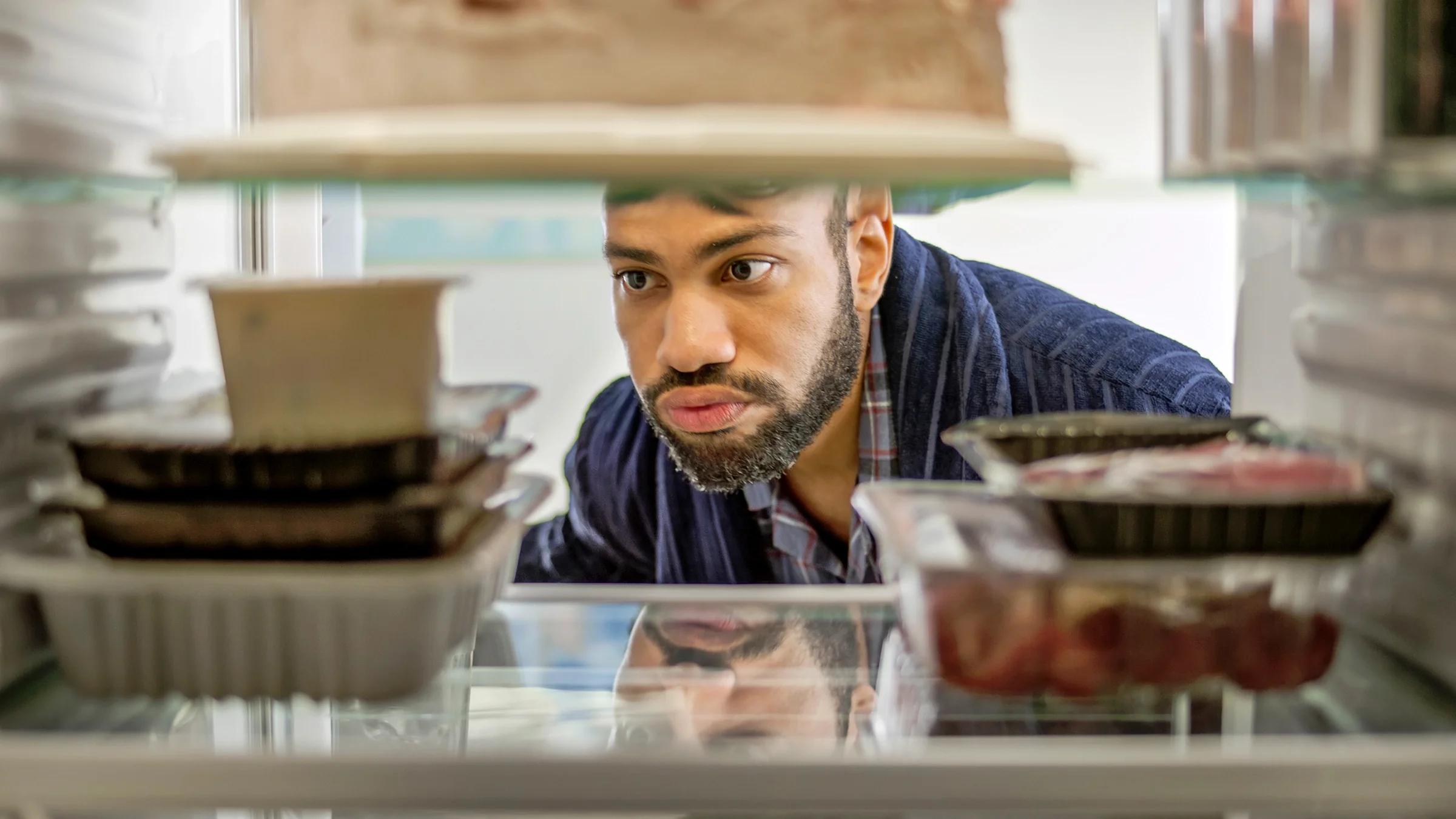 A man looks inside the refrigerator.