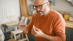 A man holding a glass of water about to take his medication.
elenaleonova/E+ via Getty Images