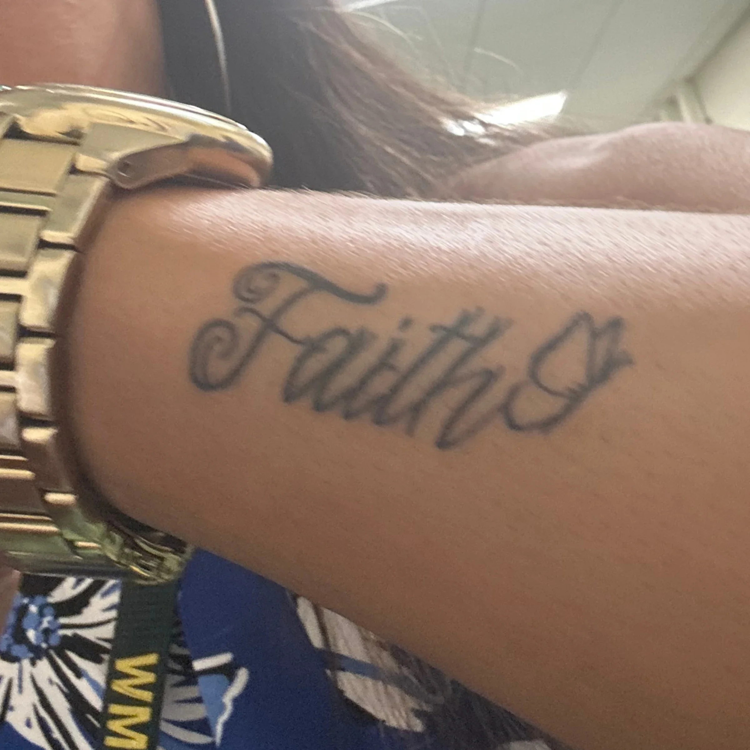 A detail shot of Tiffani Milam-White’s forearm “faith” tattoo is pictured.