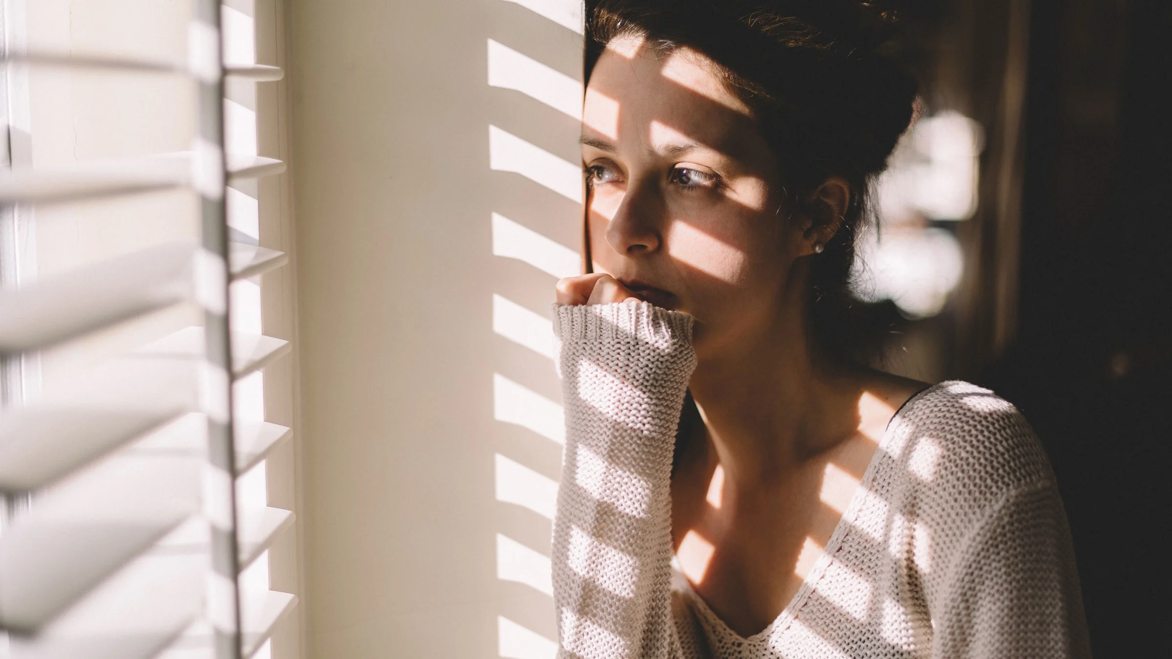 Woman looks anxiously through a window. 