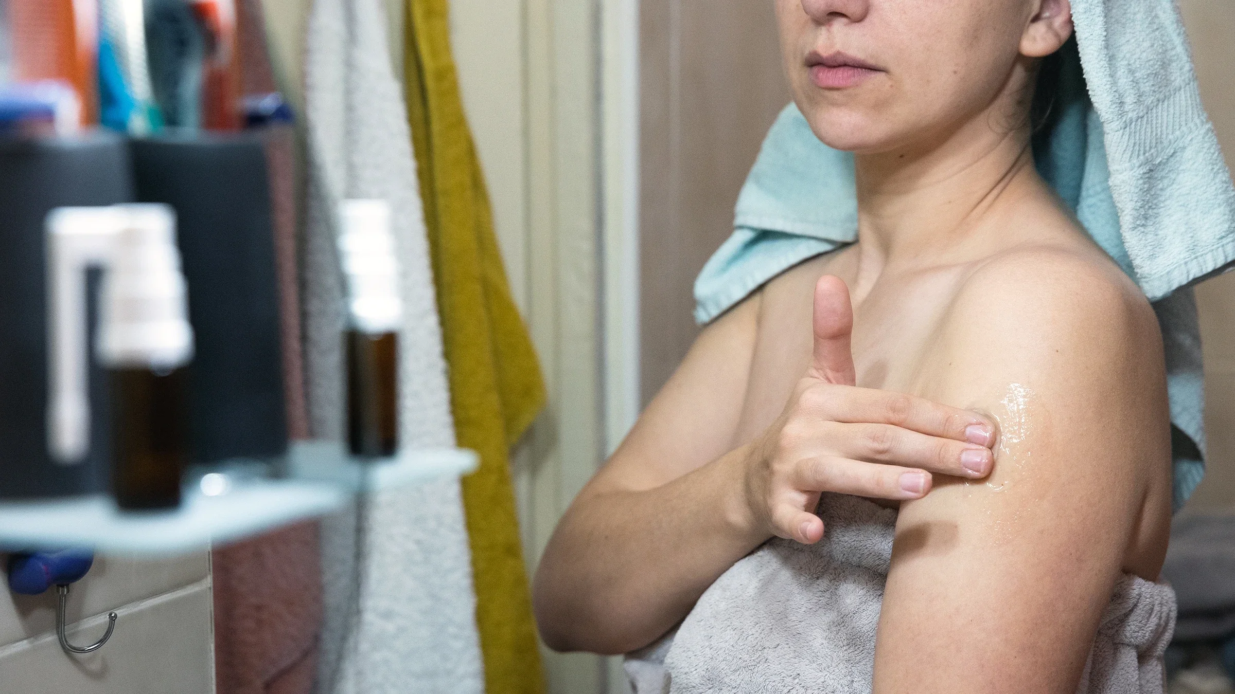 A woman rubs ointment on the outside of her upper arm.
