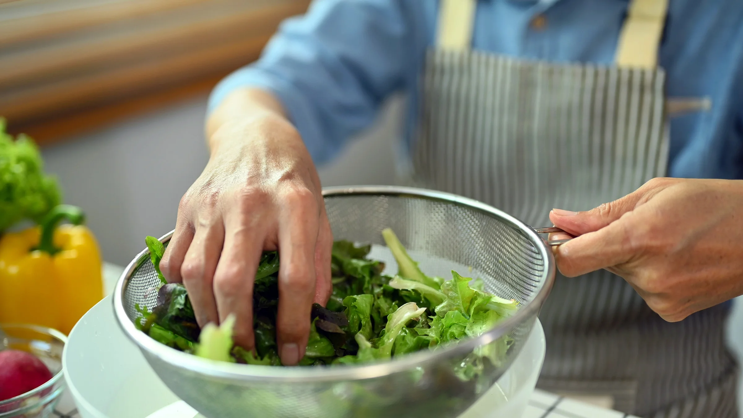 A close-up of a senior man rinsing leafy vegetables.