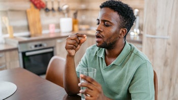 Pharmacy: man taking oral medication with water 2172368067