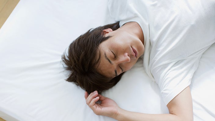 Man sleeping on his back without a pillow.