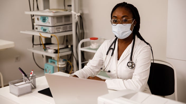 Young doctor sitting at her desk with medical equipment behind her.
