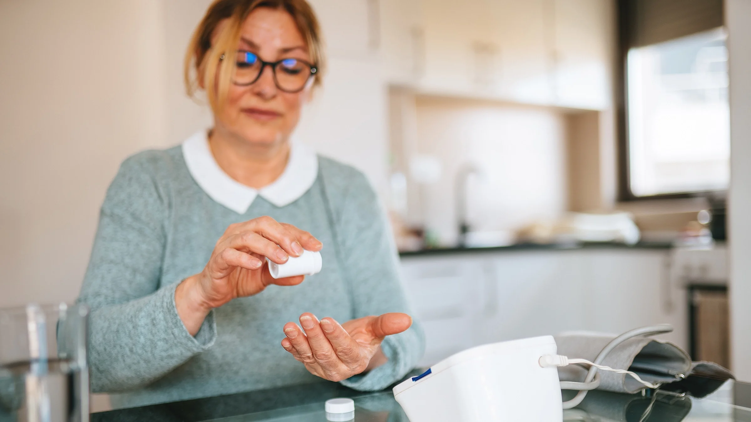 A woman is checking her blood pressure and taking medication.