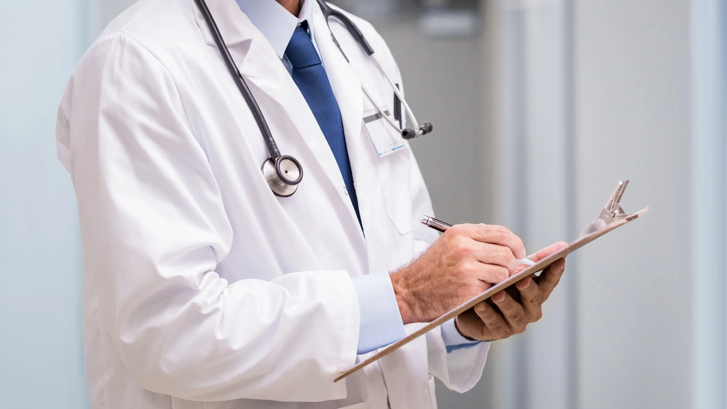 Cropped shot of a doctor writing on a clipboard.