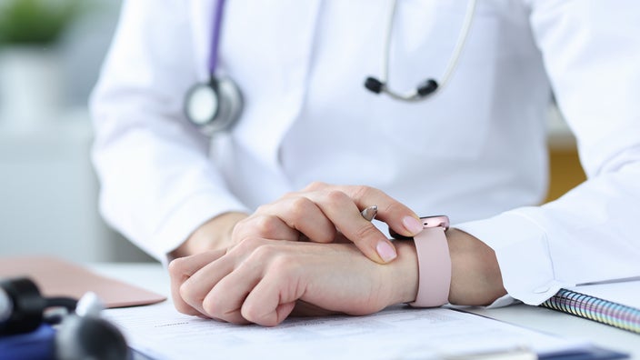 Cropped close-up shot of a doctor checking their watch.