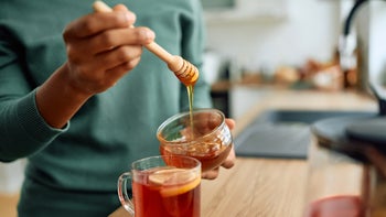 closeup adding honey to tea 2173119049