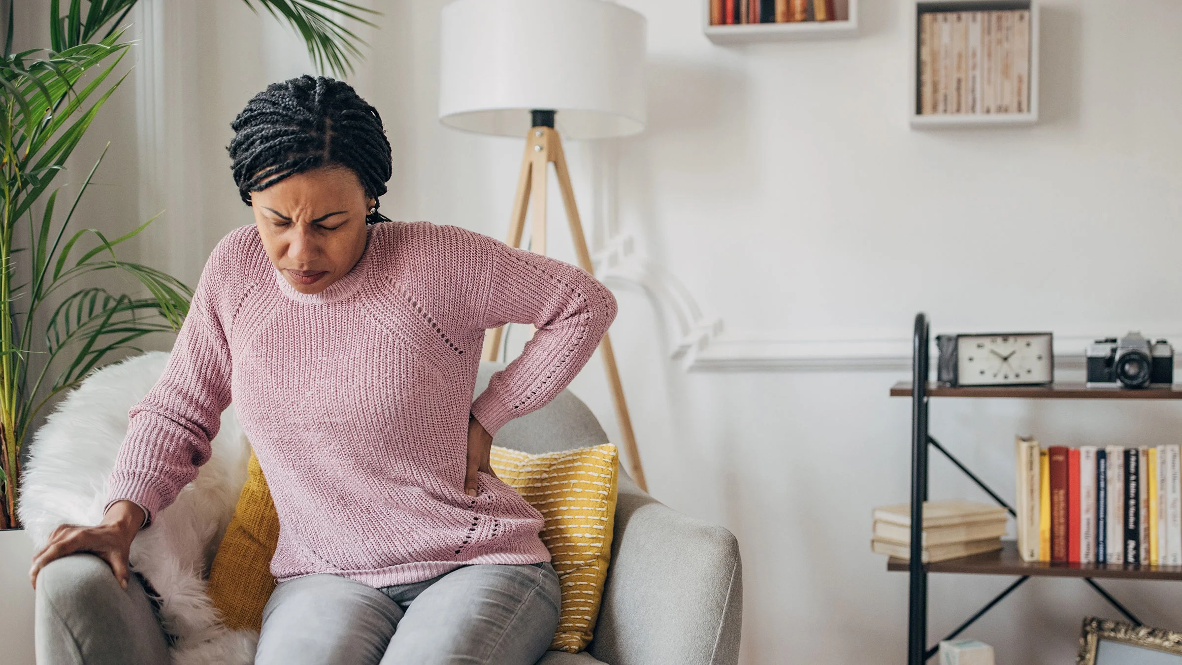 Woman having back pain while seated in her living room