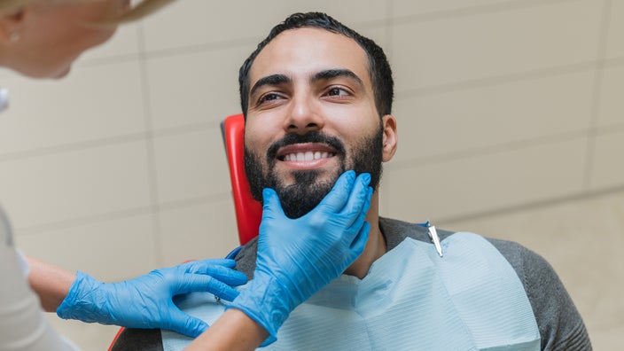 Man in dentist chair being examined by the dental hygienist.