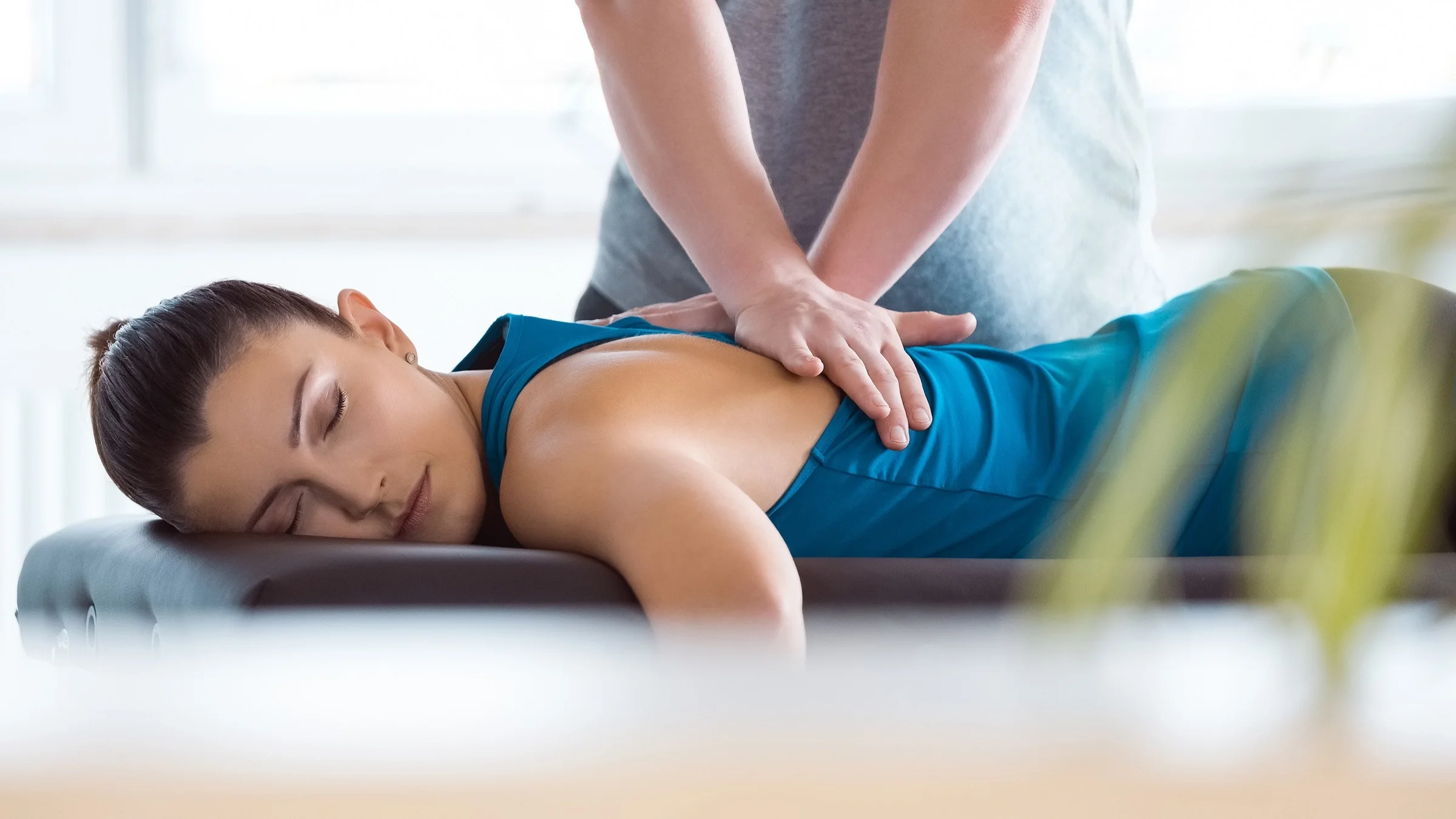 A physiotherapist massages and manipulates the muscles in a patient's upper back.