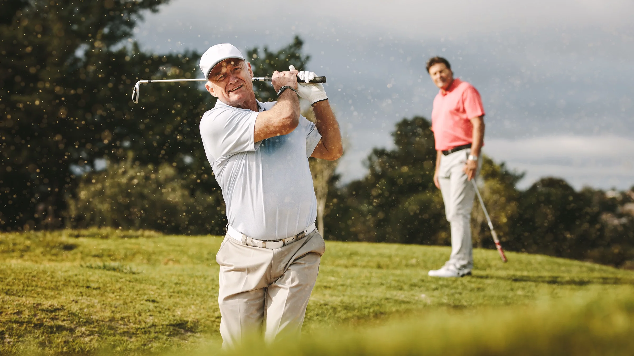 Two people play golf on a golf course.