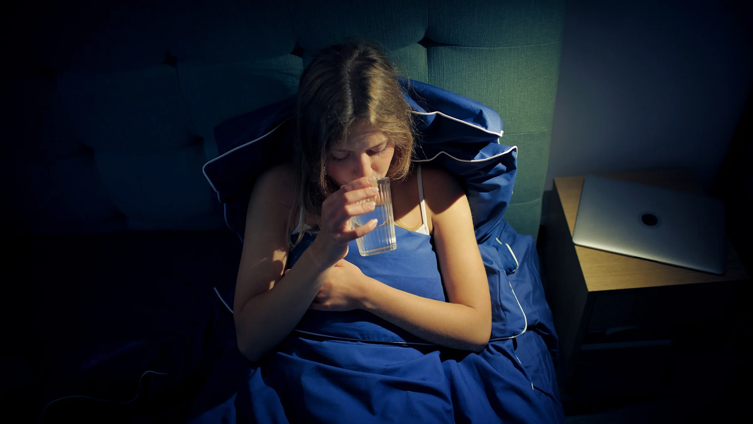 Woman in bed drinking a glass of water