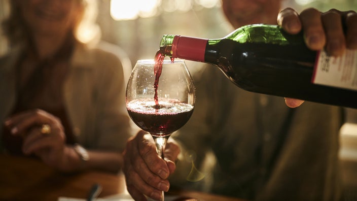 Close-up of older man pouring red wine