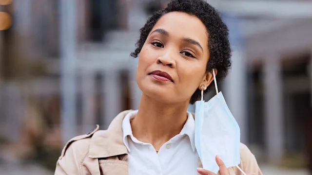 COVID-19: portrait woman taking off face mask 1440323574