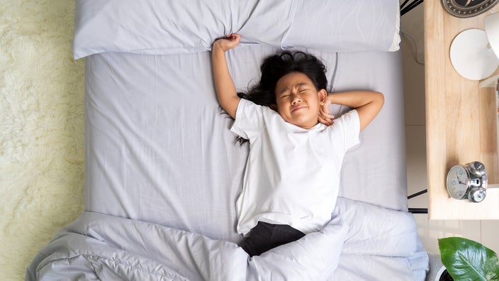 A restless child lies in bed. 