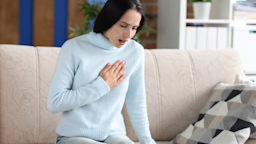 A person experiencing chest pain on their couch.
megaflopp/iStock via Getty Images Plus  