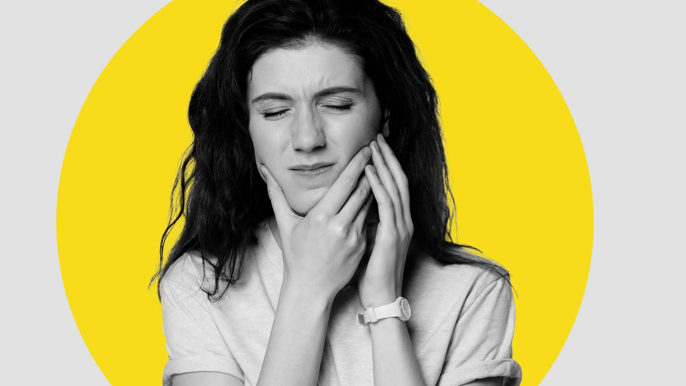 Black and white portrait of a woman holding her jaw in pain. There is an added yellow graphic circled behind her.