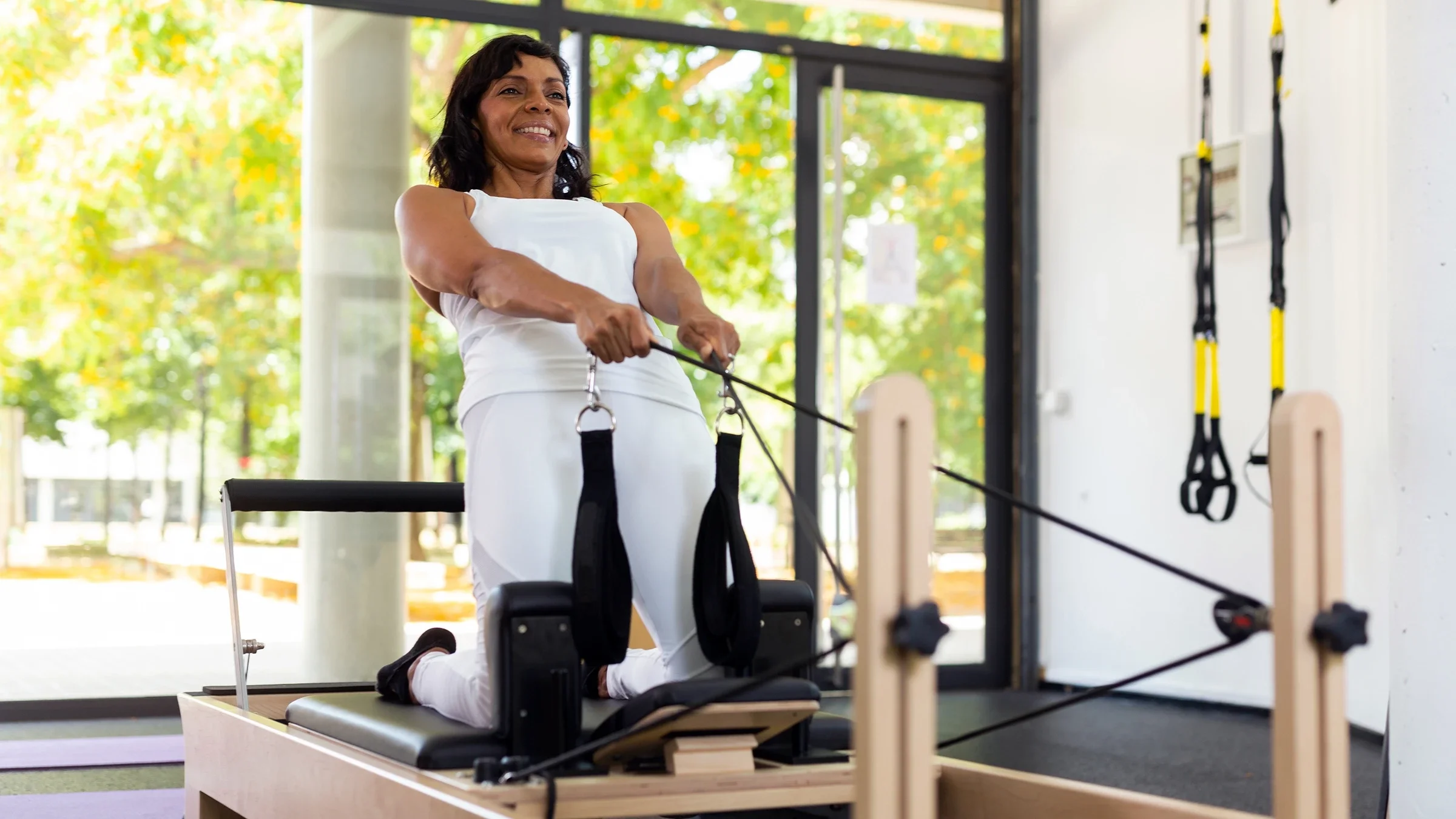 A woman is exercising on a Pilates reformer.